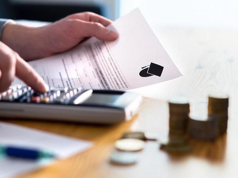 A person using a calculator and paperwork to manage college costs